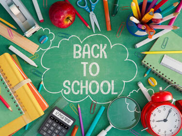 back to school on a chalkboard with random school supplies