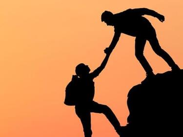 Silhouette of a climber helping a climber