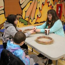 Female ISW supports two grade 5 students with their drum-making